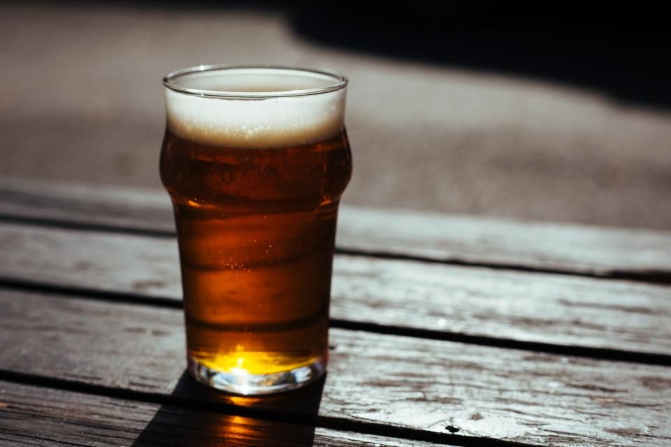 An amber pint on a weathered picnic table