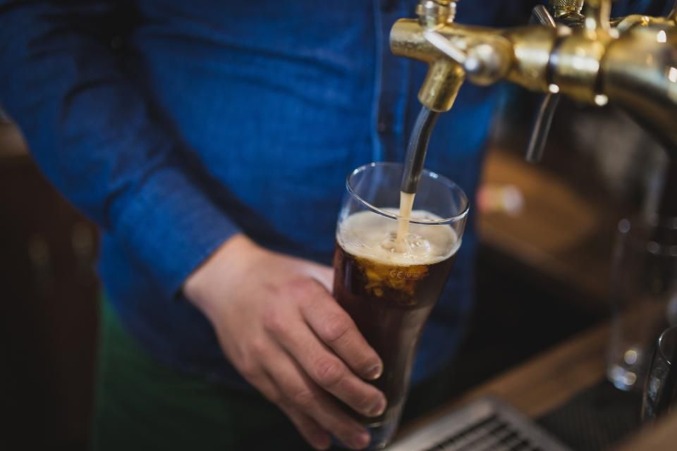 A bartender pulling a dark beer from a chrome tap